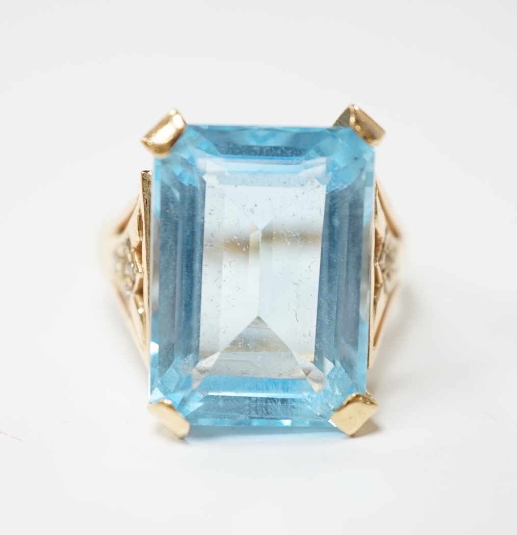 A yellow metal and single stone emerald cut blue topaz set dress ring, with ten stone diamond chip set shoulders, size U/V, gross weight 10.4 grams.